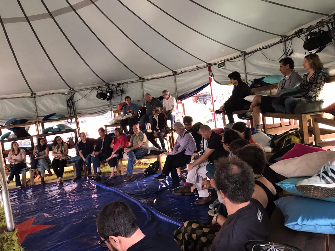 Homens e mulheres em uma tenda de circo ocupam as arquibancadas 